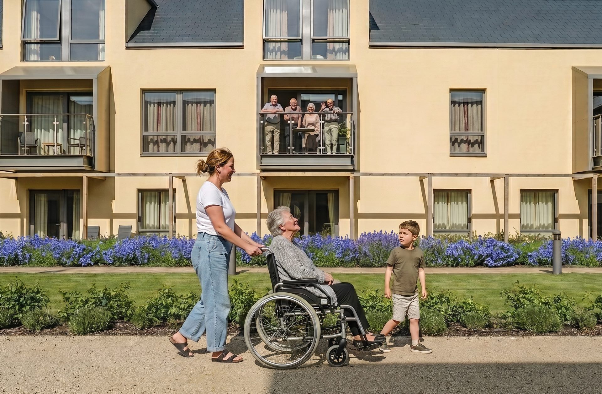 Une femme pousse une aînée en fauteuil roulant dans un EHPAD, accompagnée d'un enfant